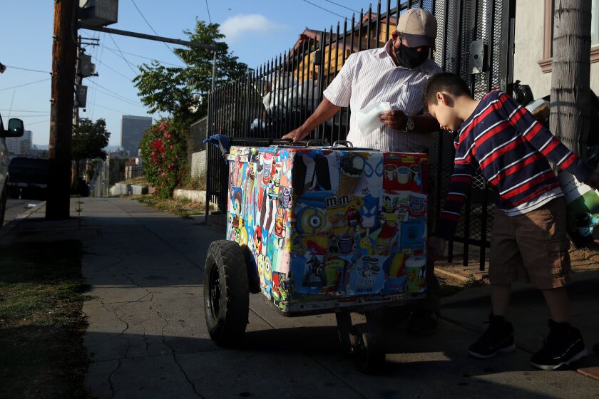 LOS ANGELES, CA - JUNE 16: Mauro Rios Parra sells a paleta to Matthew Chicas, 6, who has been purchasing from him his entire life on Tuesday, June 16, 2020 in Los Angeles, CA. Parra came to the U.S. from Mexico about 20 years ago to financially support his wife and three kids in Oaxaca and he has been selling paletas ever since. (Dania Maxwell / Los Angeles Times)