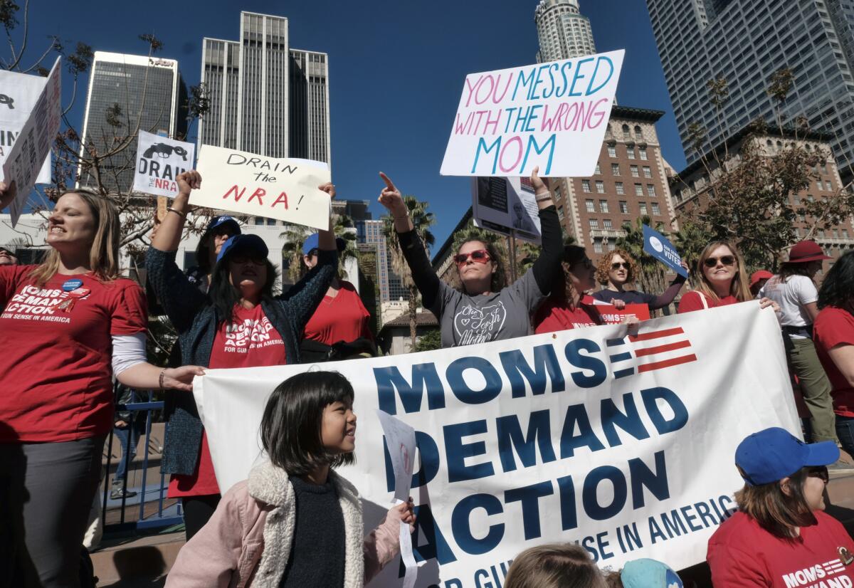 A group of mothers and kids carrying signs join in a rally against gun violence in downtown Los Angeles on Feb. 19.