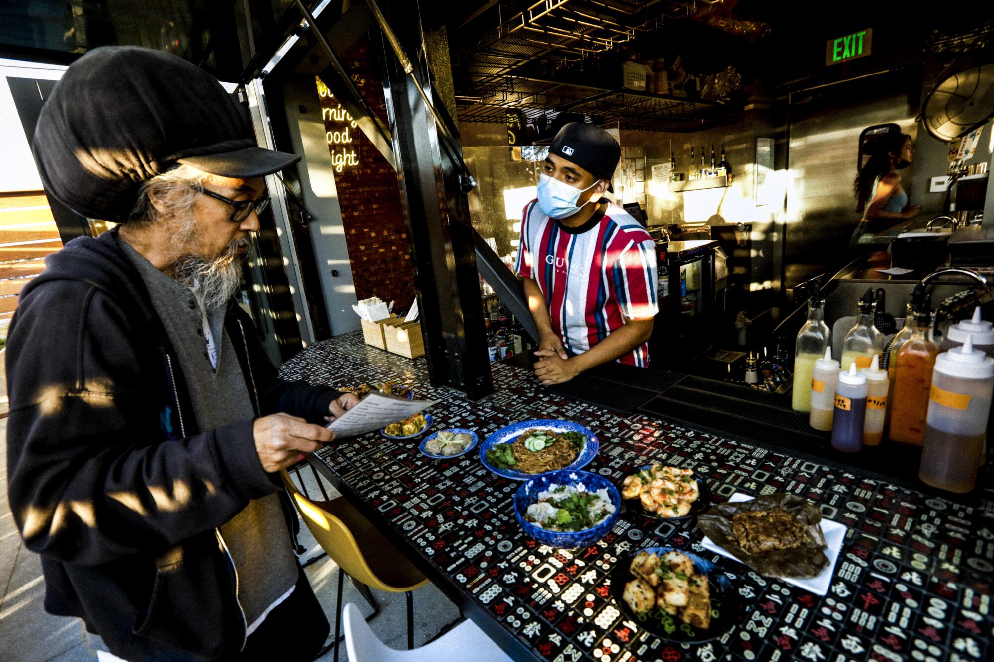 Alejandro De Anda takes a dinner order from Justin Yasutake in the bar and patio area of the Morning Nights’ restaurant.
