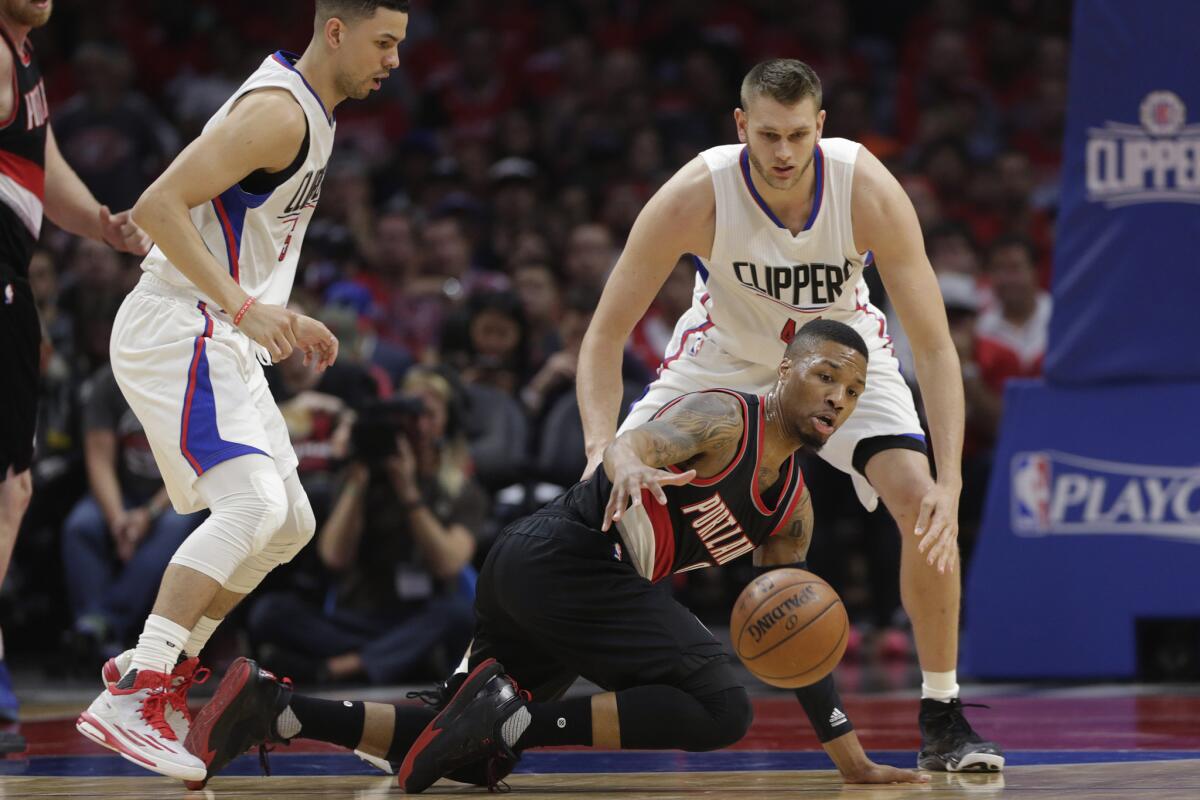 Trail Blazers guard Damian Lillard controls the ball as he falls to the floor in front of Clippers center Cole Aldrich during first half action.