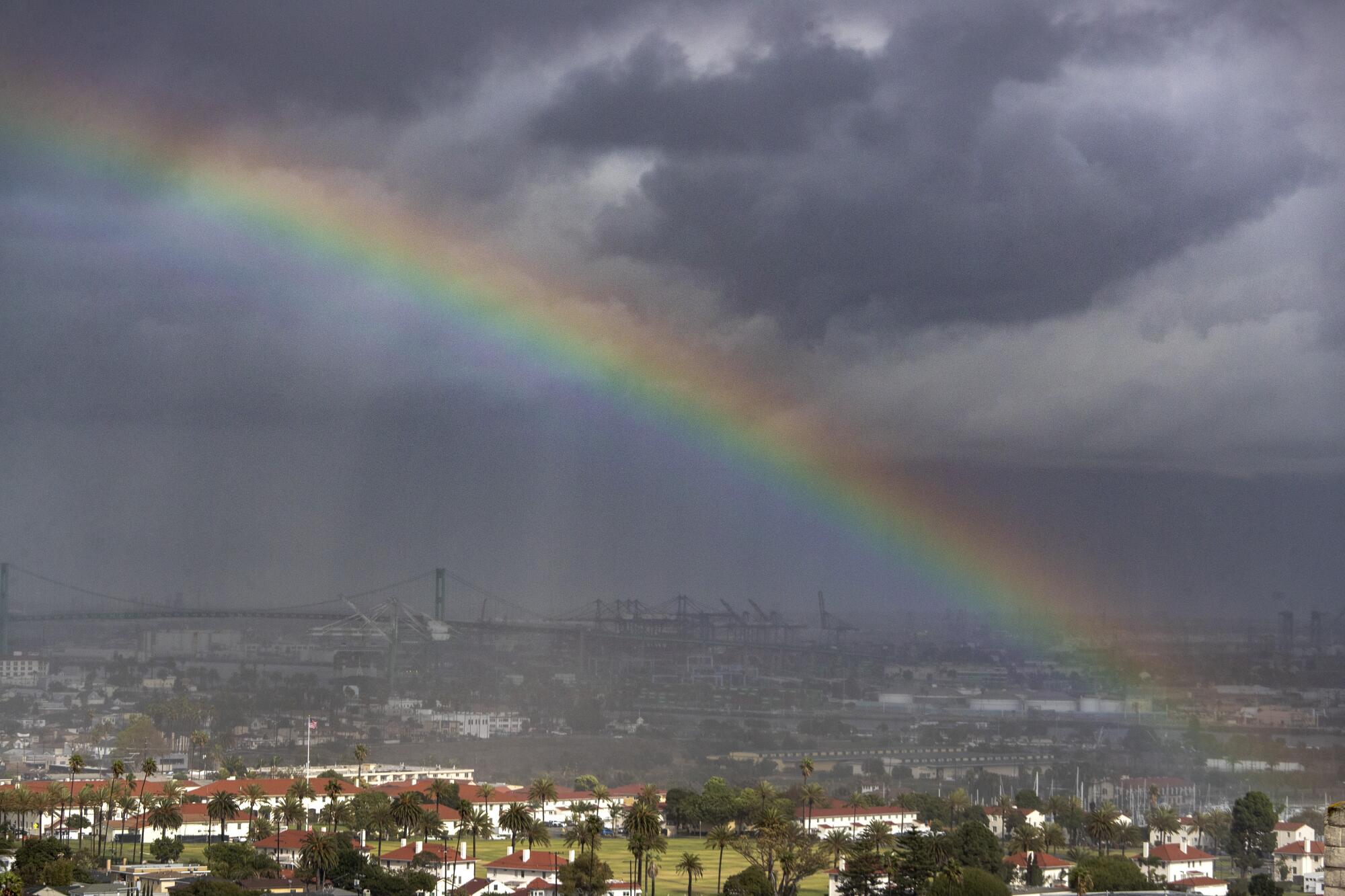 A rainbow appears amid pouring rain over a port.