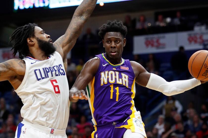 New Orleans Pelicans guard Jrue Holiday (11) passes around LA Clippers center DeAndre Jordan (6) under the basket in the second half of an NBA basketball game in New Orleans, Sunday, Jan. 28, 2018. The Clippers won 112-103. (AP Photo/Gerald Herbert)
