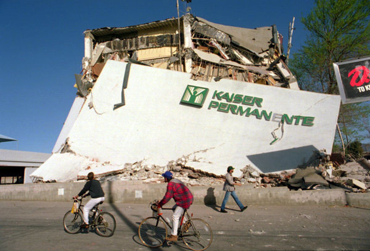 Radfahrer fahren an den Überresten eines eingestürzten Klinik- und Bürogebäudes Kaiser Permanente vorbei.