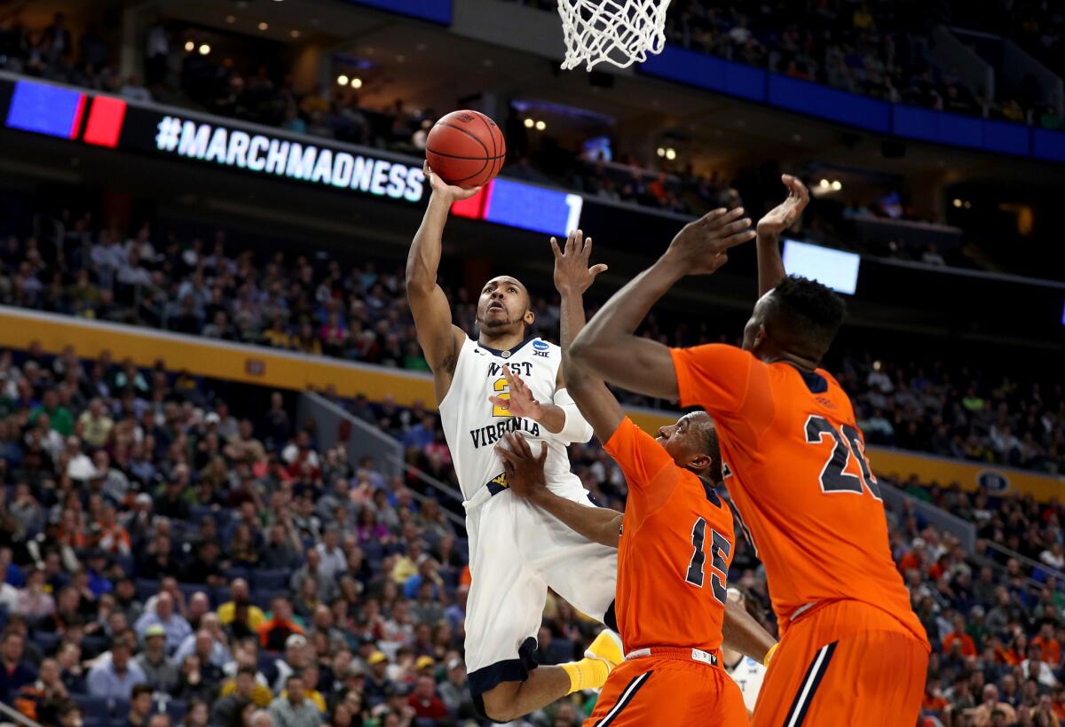West Virginia guard Jevon Carter attempts a shot over two Bucknell defender during the first half.