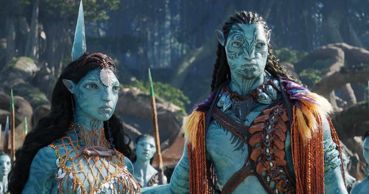 Husband and wife sea-faring aliens stand together in a scene from "Avatar: The Way of Water."