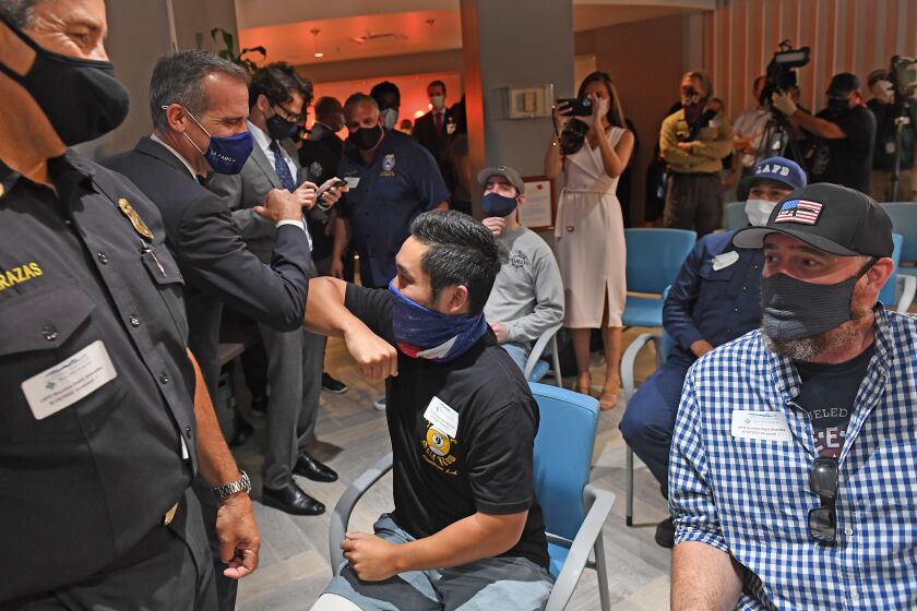 LOS ANGELES, CALIFORNIA AUGUST 19, 2020-L.A. City Firefighter Andrew Tom, who has burns to his waist and legs, greets L.A. Mayor Eric Garcetti at a reunion for injured firefighters at the Grossman Burn Center in West Hills Wednesday. The firefighters were caught in a ball of fire after an explosion at a buisness in Downtown Los Angeles in May. (Wally Skalij/Los Angeles Times)
