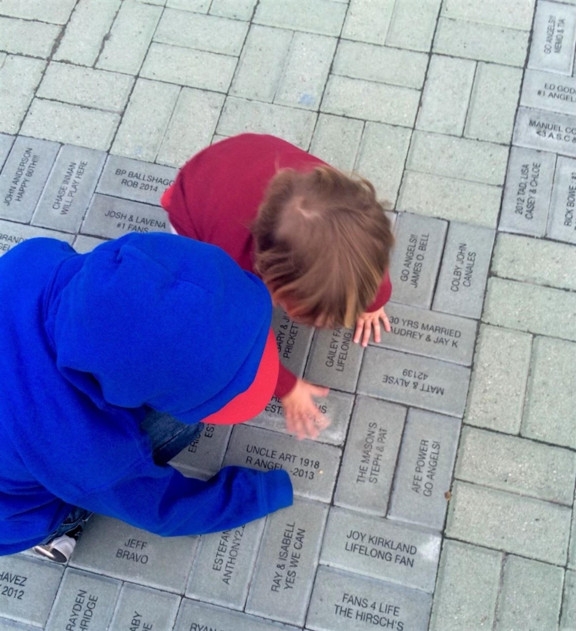 Tawyna Johnson Hesse’s children crouch to touch the brick dedicated to her late Uncle Art.