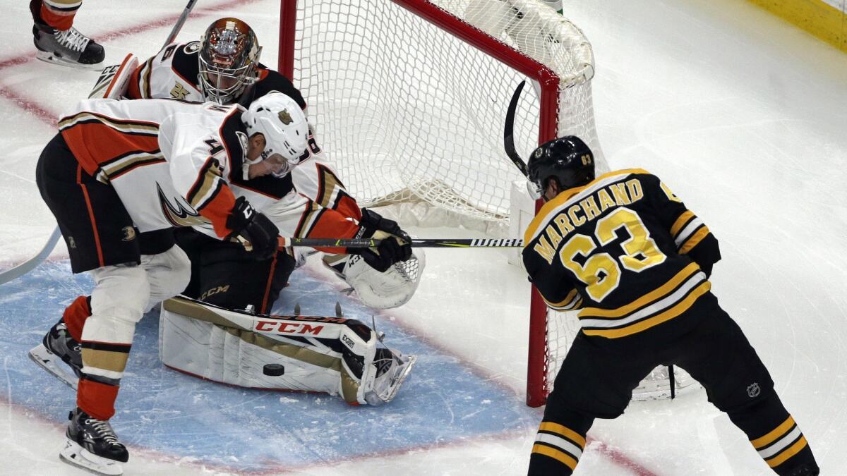 Ducks goaltender John Gibson makes a save as defenseman Hampus Lindholm (47) helps defend against a shot by Boston Bruins left wing Brad Marchand (63) in the first period.