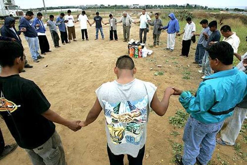 Farmworkers join hands in prayer at their camp in Carlsbad, in north San Diego County. Local churches and volunteers provide spiritual support, food and clothing.