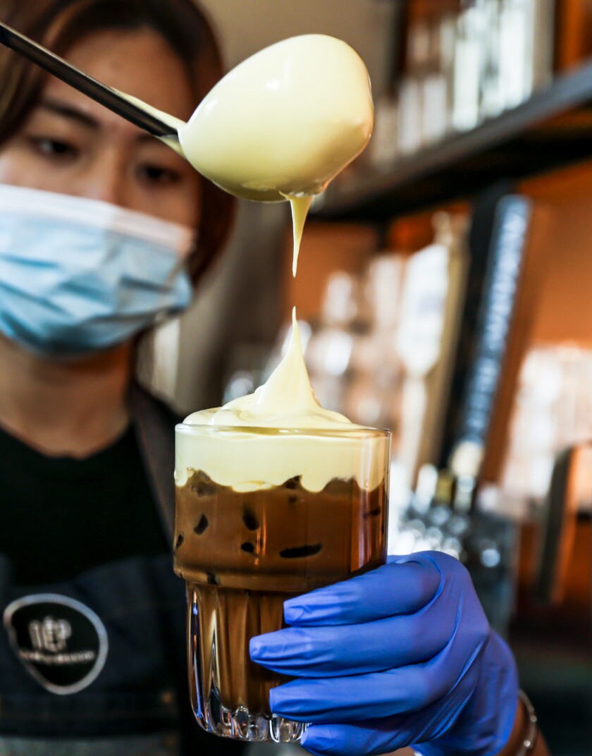 A barista pours egg foam while making coffee.