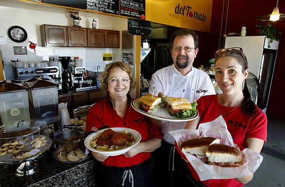 Del Tomate owners, from left, Susana and Guillermo Giacobbe and their daughter Valeria, holding dishes of Argentine-Italian food.