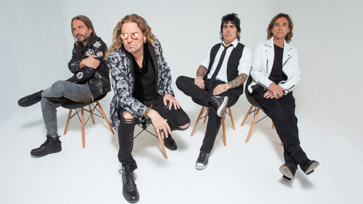 Four bandmates seated in chairs.