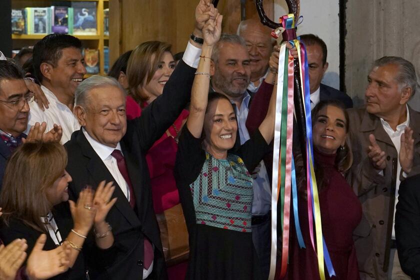 FILE - Mexican President Andres Manuel Lopez Obrador raises the hand of Claudia Sheinbaum, the ruling party's candidate for the upcoming presidential elections, during a ceremony to hand over the party's command staff, in Mexico City, Sept. 7, 2023. Mexico’s ruling party named its candidates for eight governorships and the mayor of Mexico City, on Saturday, Nov. 11, 2023, to compete in the country's June 2024 general elections. (AP Photo/Marco Ugarte, File)