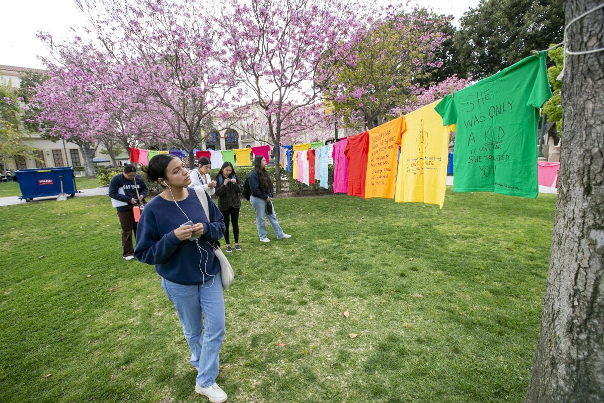 Kassandra Dominguez reads T-shirts hung in the quad at Fullerton College on April 18.