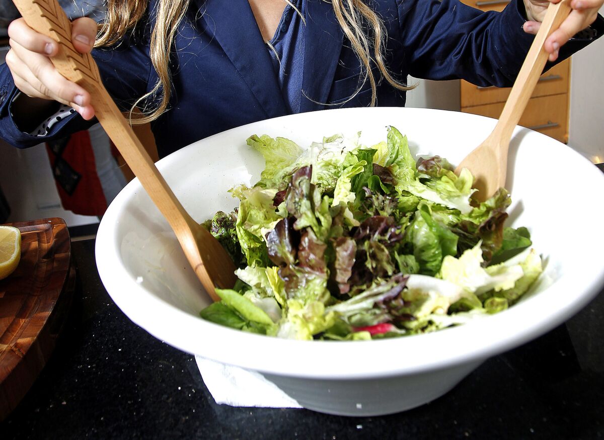 Noa Perry Lang mixes a French salad in a white bowl.