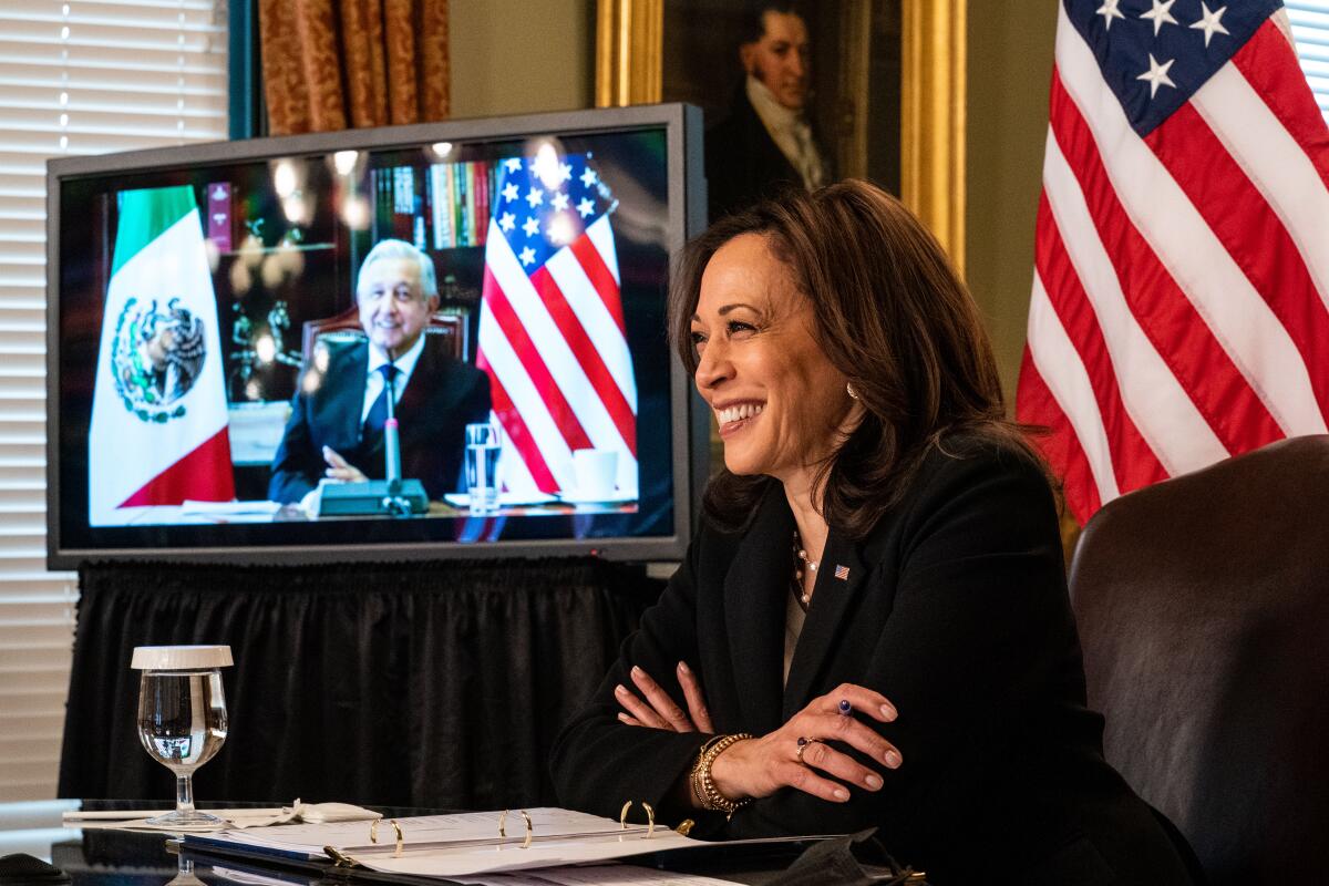 Andrés Manuel López Obrador is seen on a monitor next to Vice President Kamala Harris.