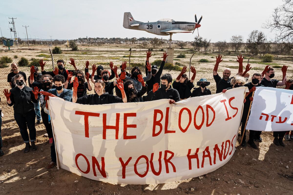Left-wing activists protesting outside an Israeli military base hold a banner that says "The blood is on your hands"