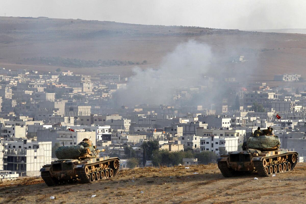 Turkish tanks hold their position on a hilltop on the outskirts of Suruc on the Turkey-Syria border, after an airstrike in Kobani, Syria.