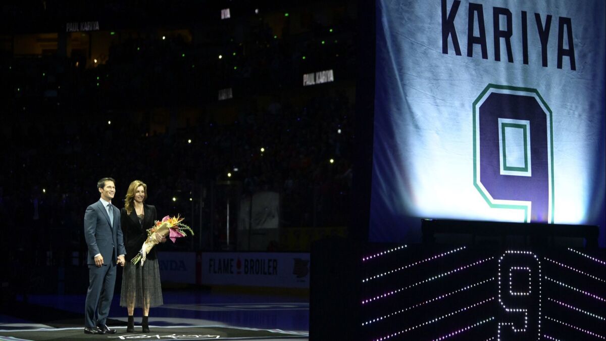Former Ducks player Paul Kariya, left, stands with his girlfriend Valerie Dawson and watches as his jersey is retired prior to the game against the Buffalo Sabres on Sunday.