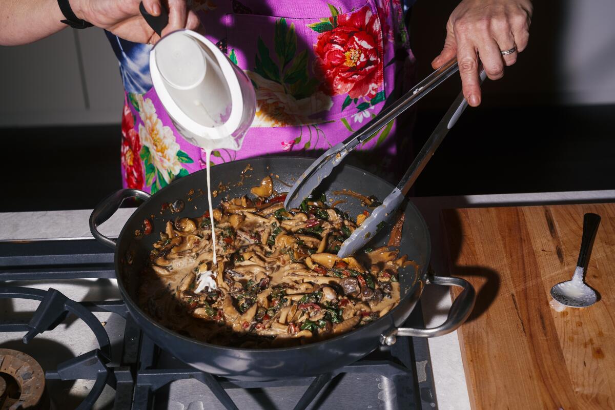 Los Angeles Times Test Kitchen Coordinator Julie Giuffrida adds cream to a pan of sauteed mushrooms.