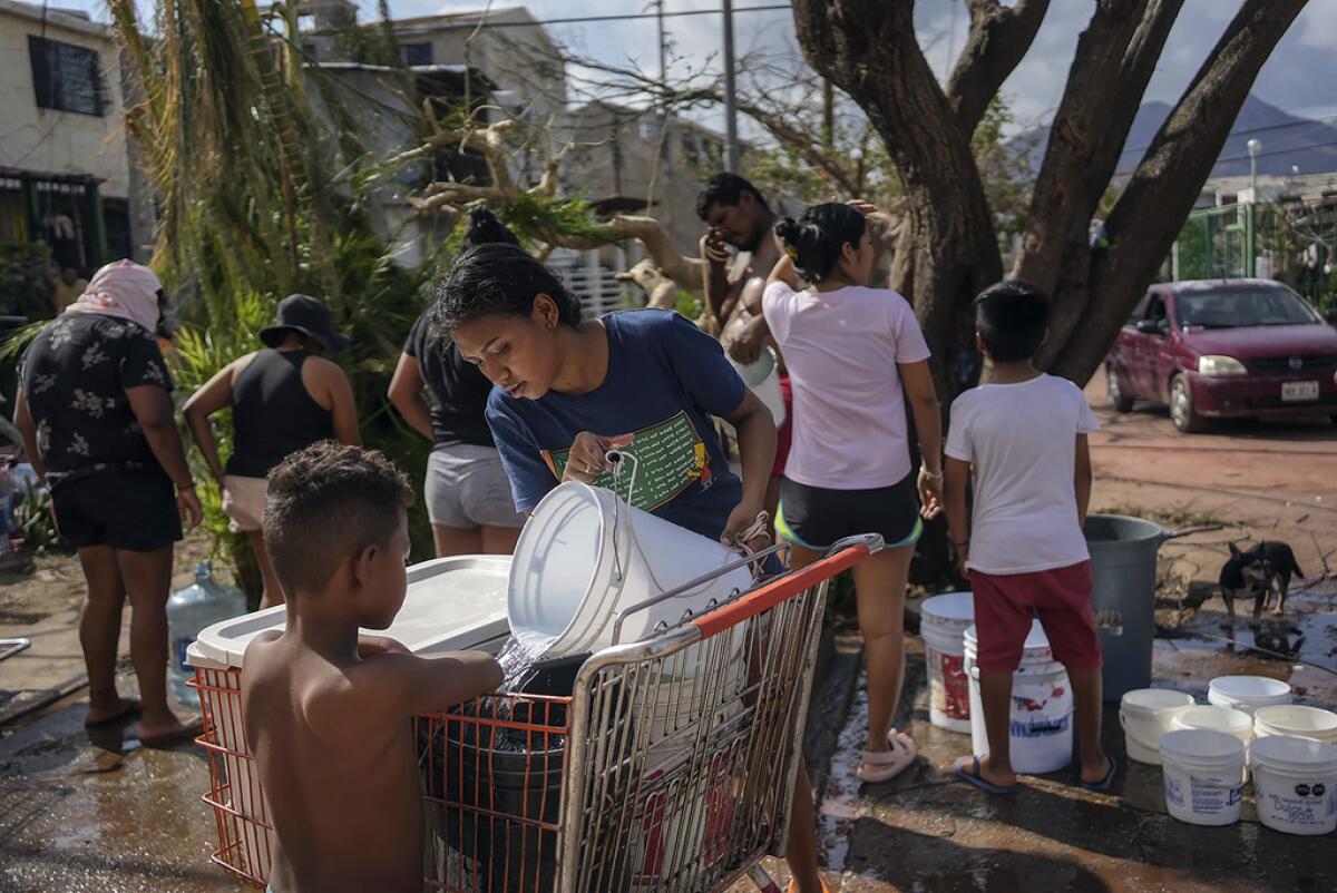 Unos hermanos recolectan agua de un pozo 