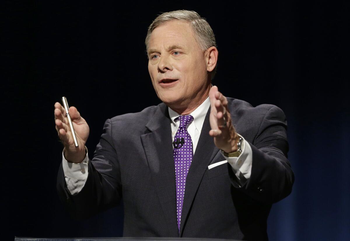 Sen. Richard Burr gestures while speaking, holding a pen in one hand