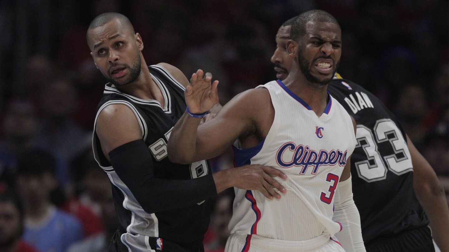 Clippers points guard Chris Paul, center, holds his left leg after suffering a strained hamstring in front of San Antonio Spurs teammates Patty Mills and Boris Diaw during the Clippers' 111-109 victory over the San Antonio Spurs in Game 7 of the Western Conference quarterfinals at Staples Center on May 2, 2015.