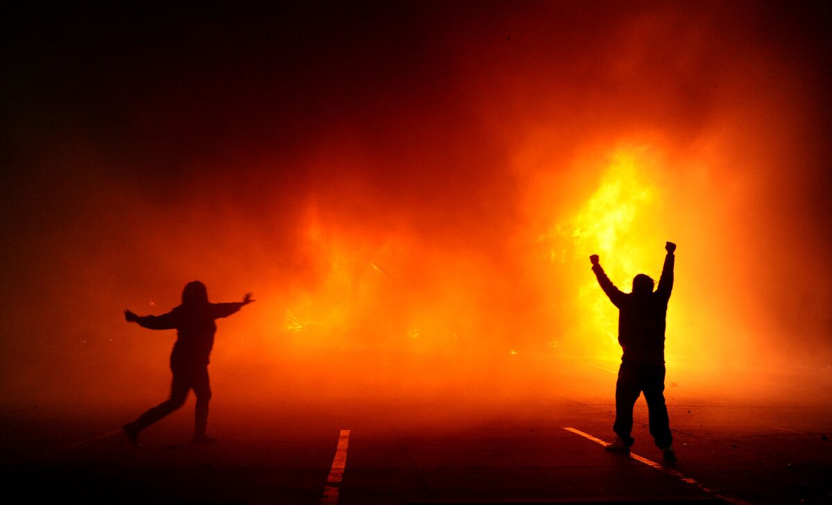 Protesters celebrate as the Auto Zone building burns on West Florissant Avenue after a grand jury decision in Ferguson, Mo.