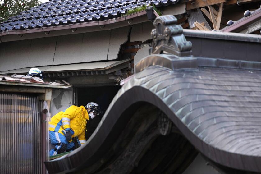 Police officers go into a building at the premises of a temple to search for victims in Wajima in the Noto peninsula, facing the Sea of Japan, northwest of Tokyo, Saturday, Jan. 6, 2024, following Monday's deadly earthquake. (AP Photo/Hiro Komae)