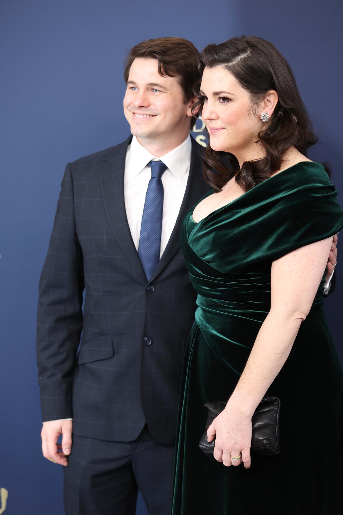 Jason Ritter wearing a suit stands beside Melanie Lynskey in an evening gown