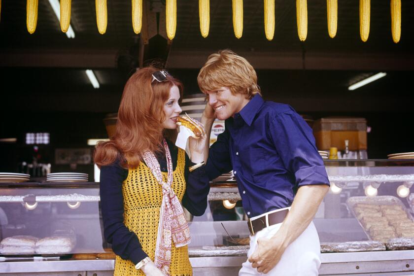 1970s Redhead Woman Wearing Crochet Vest Eating A Hot Dog With Blonde Man At Concession Hamburger Stand On Coney Island Ny USA (Photo by Photo Media/Classicstock/Getty Images)