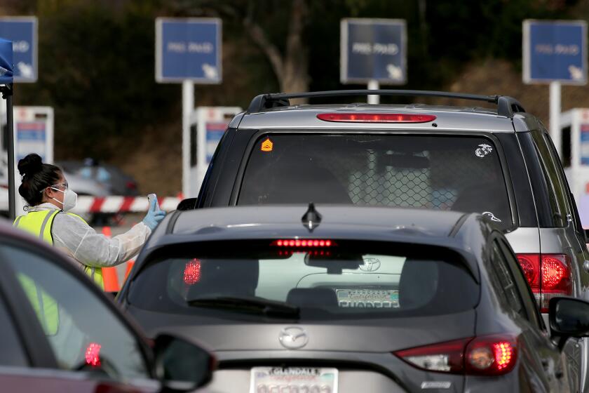 LOS ANGELES, CALIF. - DEC. 21, 2021. People seeking coronavirus tests line up to access a Curative testing site in the parking lot of Dodger Stadium in Los Angeles on Tuesday, Dec. 21, 2021. (Luis Sinco / Los Angeles Times)