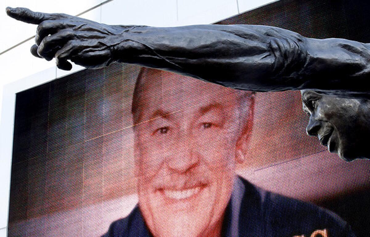 An image of Jerry Buss overlooks a statue of Lakers great Magic Johnson outside of Staples Center.