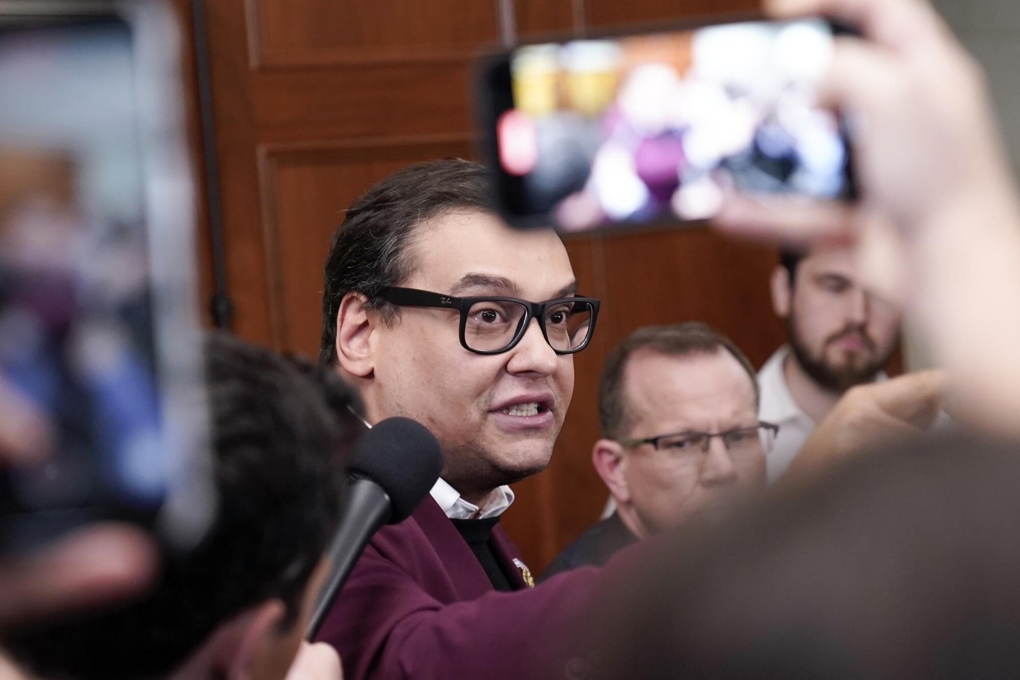 George Santos speaks as someone holds up a microphone.