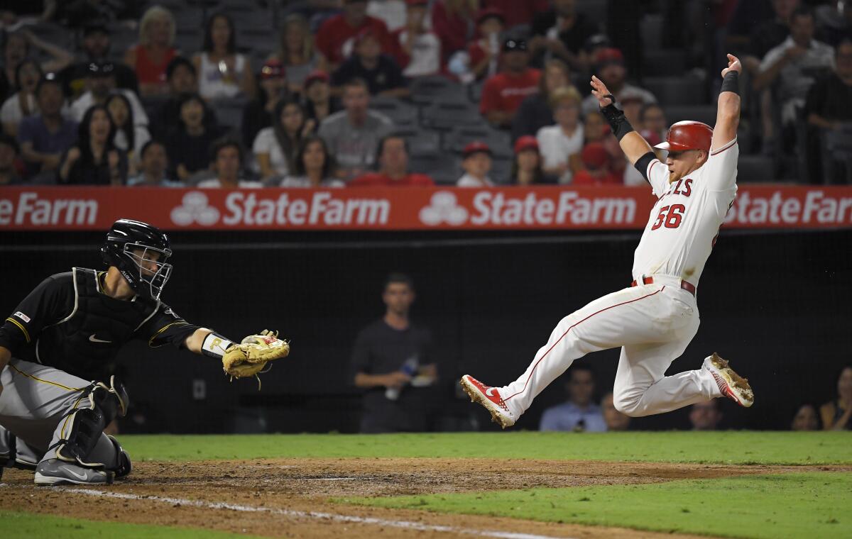 Angels' Kole Calhoun, right, slides before being tagged out by Pittsburgh Pirates catcher Jacob Stallings while trying to score on a ball hit by Matt Thaiss during the fifth inning on Tuesday at Angel Stadium.