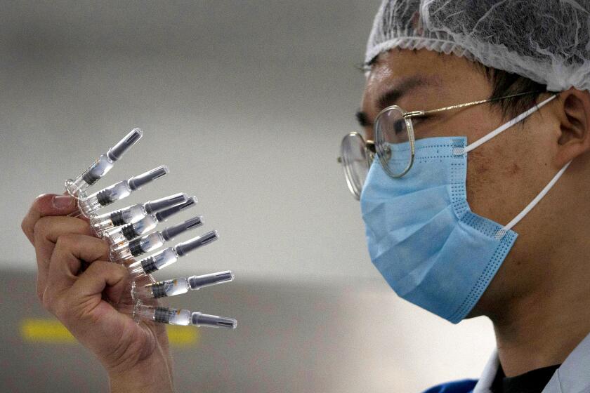 In this Sept. 24, 2020, file photo, an employee manually inspects syringes of the SARS CoV-2 Vaccine for COVID-19 produced by Sinovac at its factory in Beijing. China is rapidly increasing the number of people receiving its experimental coronavirus vaccines, with a city offering one to the general public and a biotech company providing another free to students going abroad. (AP Photo/Ng Han Guan, File)