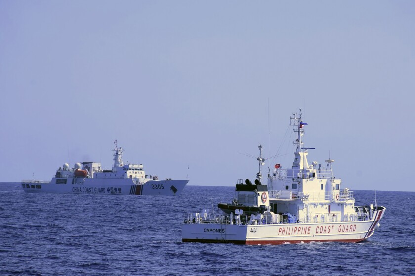 In this photo provided by the Philippine Coast Guard, a Chinese Coast Guard ship sails near a Philippine Coast Guard vessel during its patrol at Bajo de Masinloc, 124 nautical miles west of Zambales province, northwestern Philippines on March 2, 2022. A Chinese coast guard ship last month maneuvered for days near a research vessel deployed by Philippine and Taiwanese scientists to undertake a crucial survey of undersea fault lines west of the northern Philippines, sparking concerns among the scientists on board, officials said Thursday, April 7, 2022. (Philippine Coast Guard via AP)