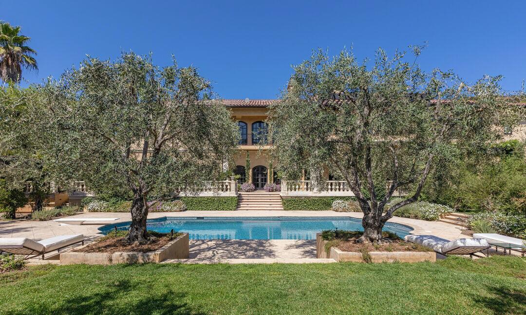 The backyard has a swimming pool and trees and a lawn.