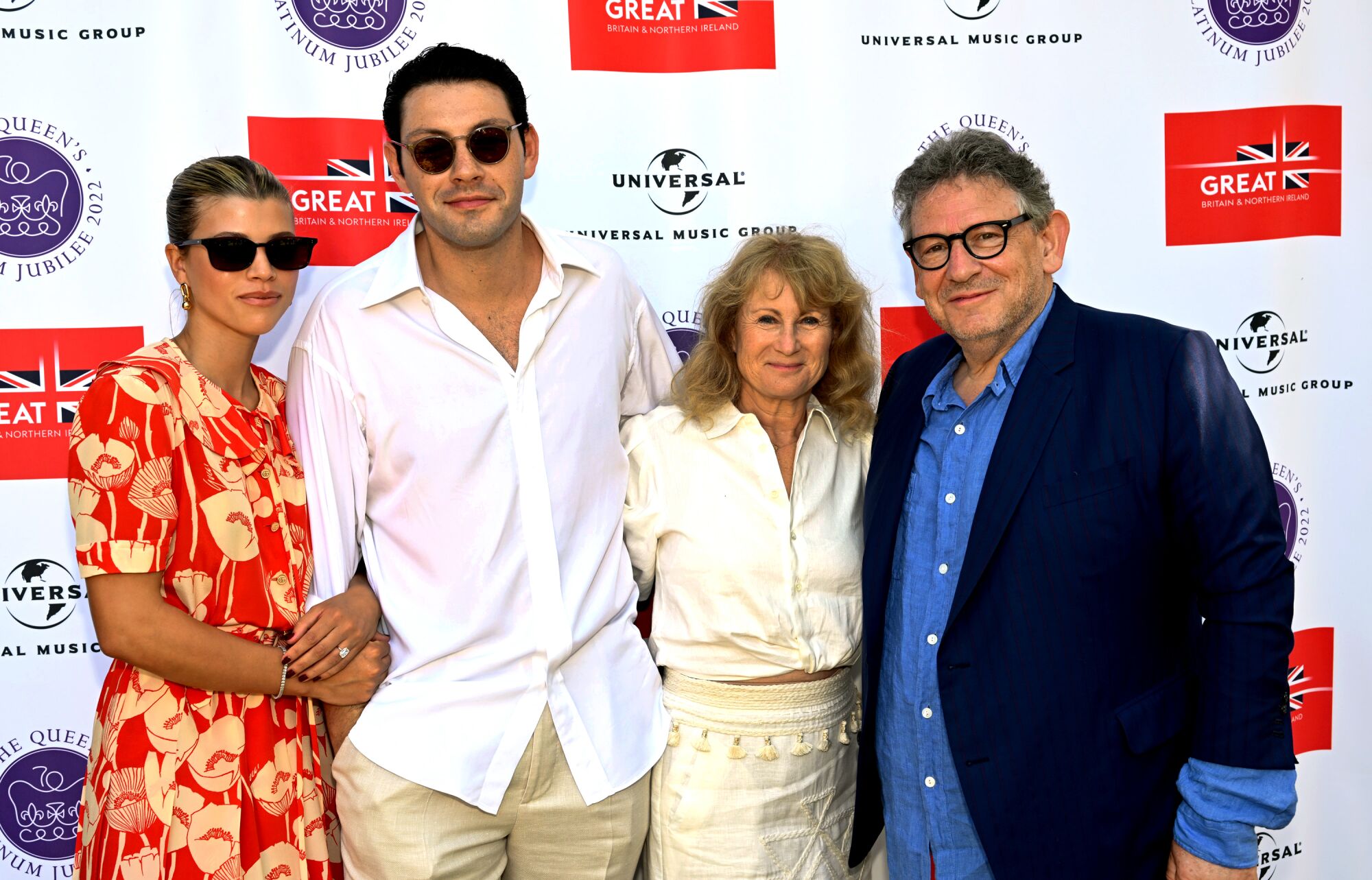 Four people pose for a photo on a red carpet