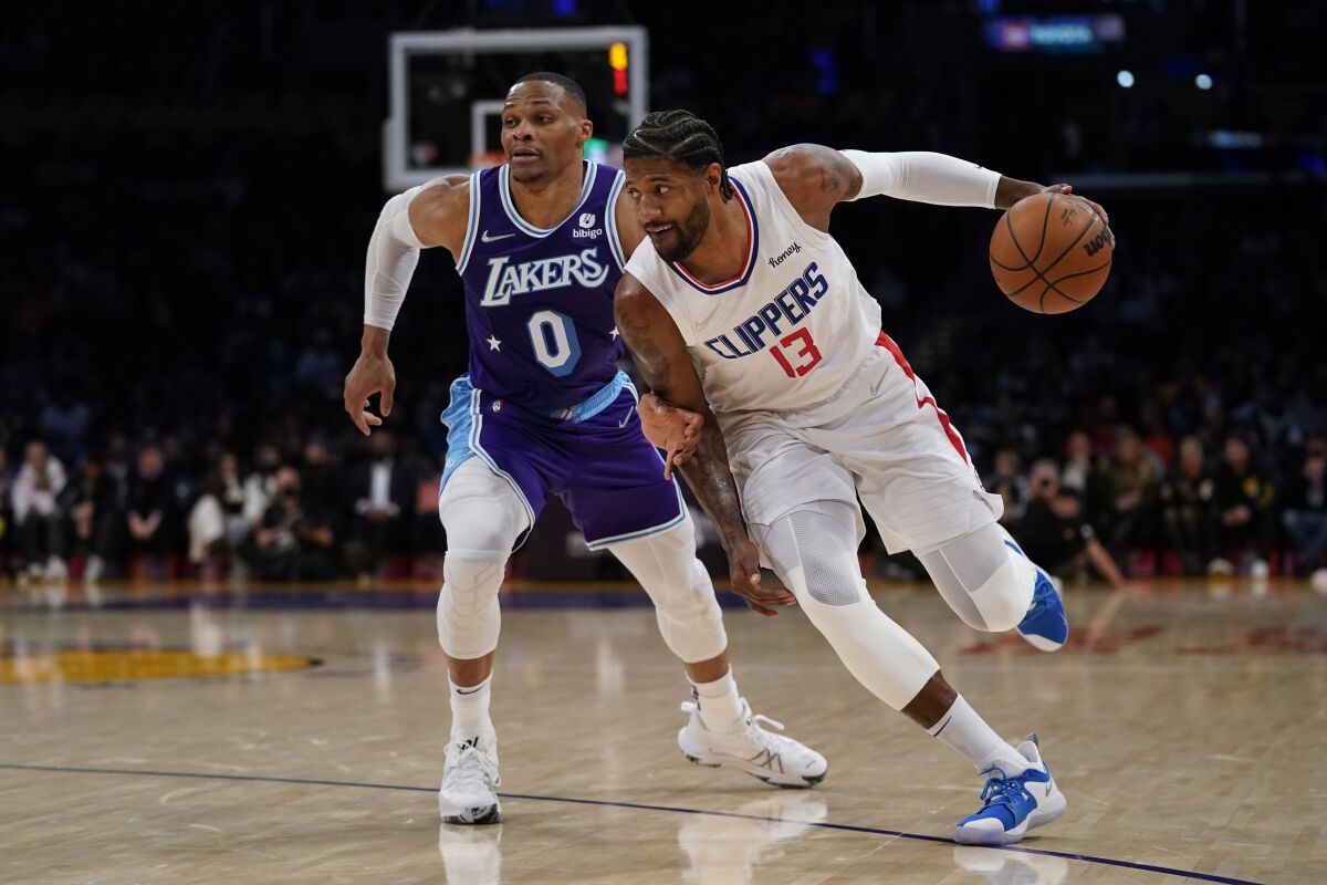 Los Angeles Lakers guard Russell Westbrook (0) defends against Los Angeles Clippers guard Paul George (13) during the first half of an NBA basketball game in Los Angeles, Friday, Dec. 3, 2021. (AP Photo/Ashley Landis)