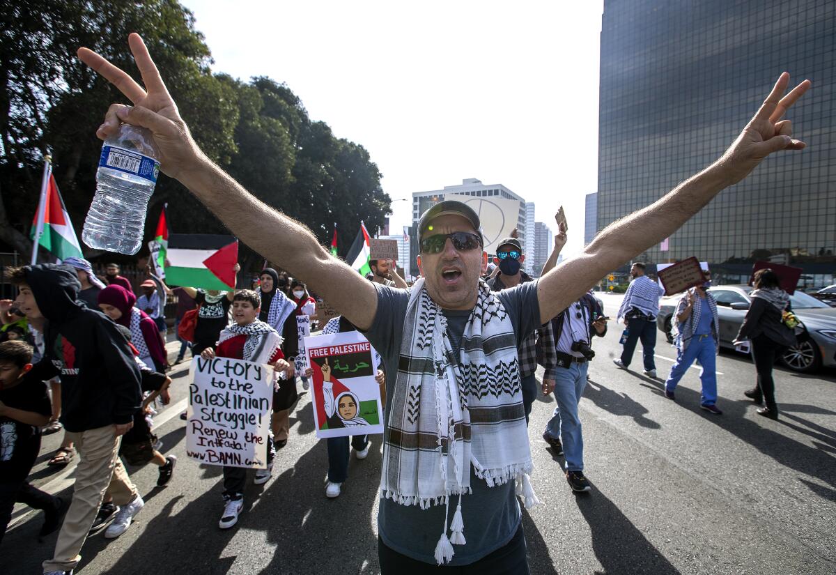 A man raises both arms as he marches with others down a city street.