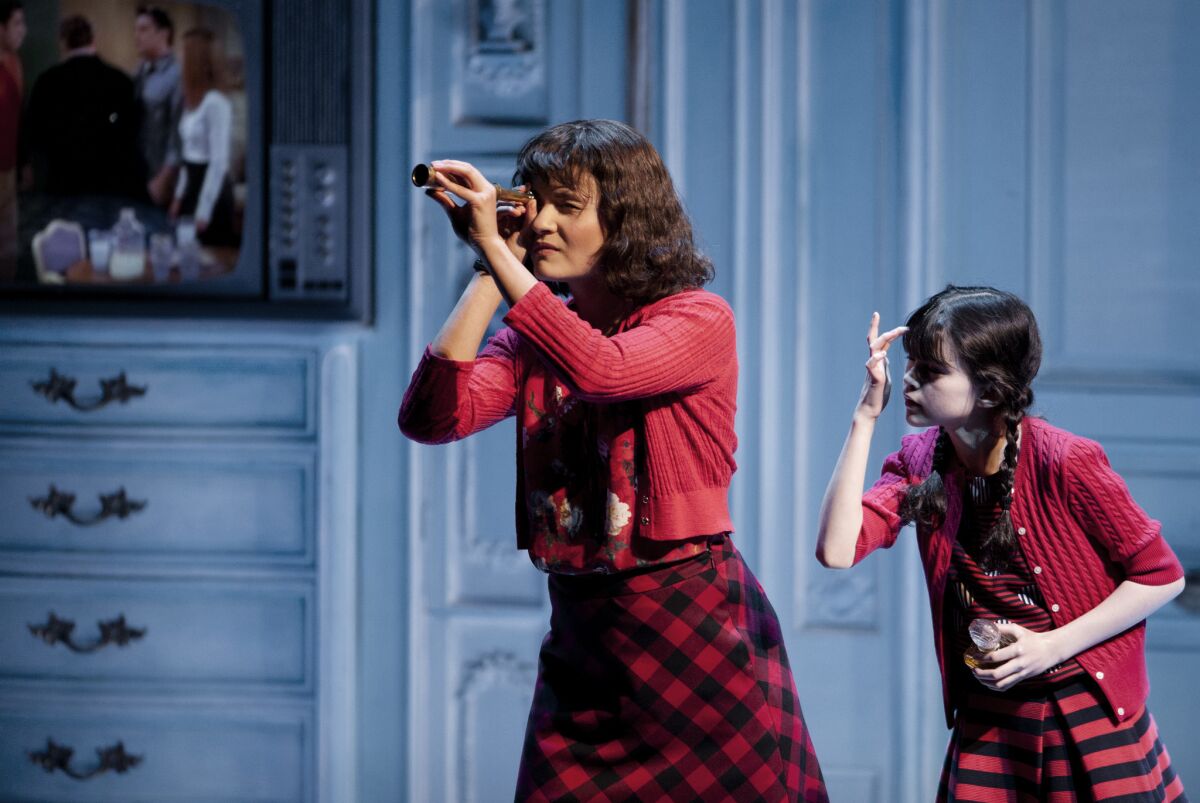 Amélie (Phillipa Soo), observed by her younger self (Savvy Crawford), makes a discovery in "Amélie, A New Musical" at the Ahmanson Theatre.