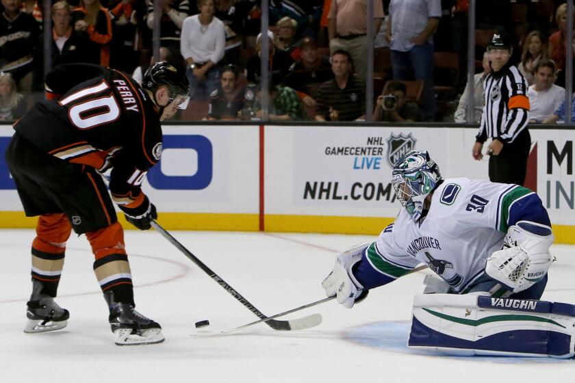 Canucks goalie Ryan Miller knocks the puck away from Ducks right wing Corey Perry in a shootout. The Canucks outscored the Ducks in the shootout, 2-1.