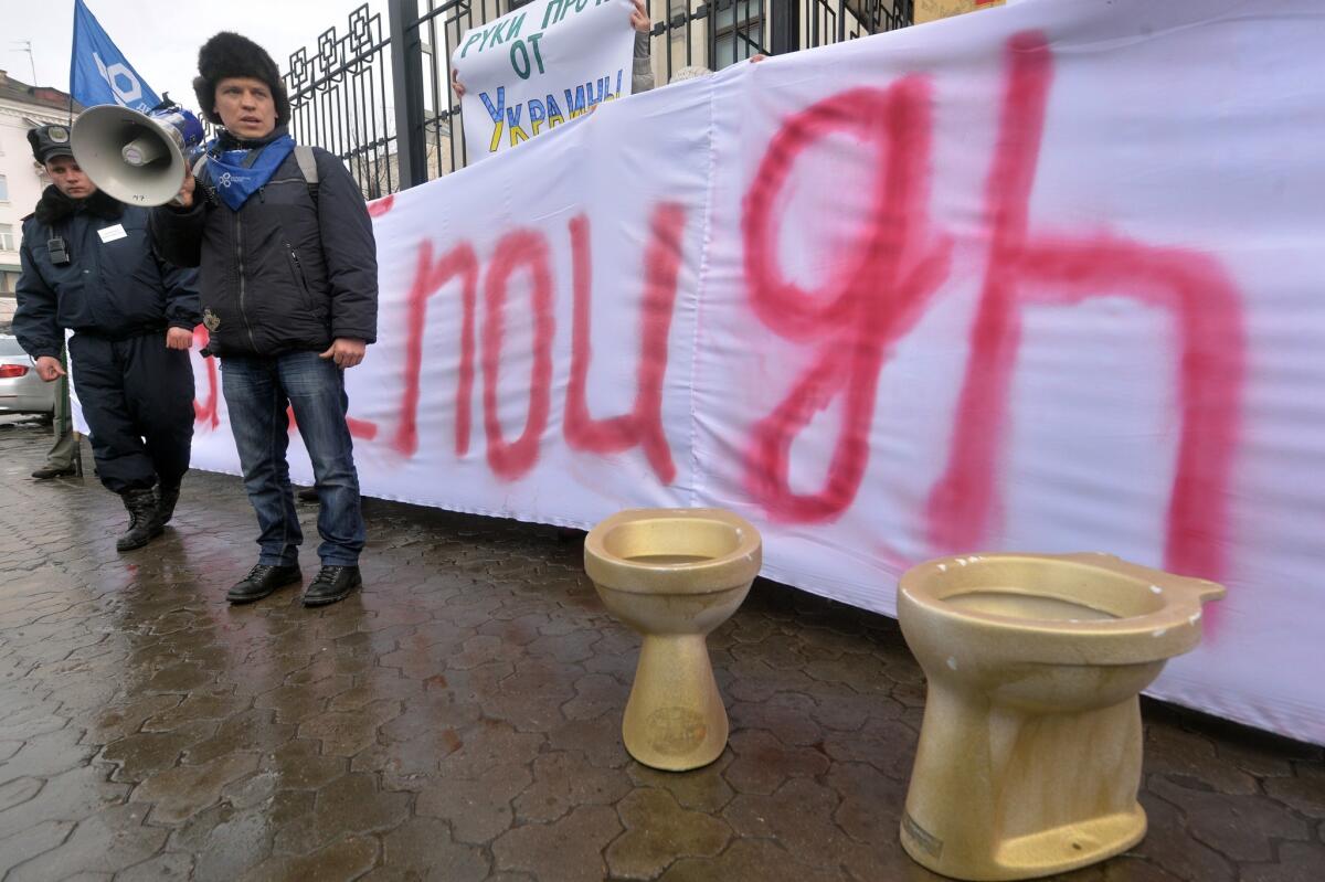 An activist chants slogans outside the Russian Embassy in Ukraine in February while standing next to symbolic golden toilets, a reference to the rumored excesses of then-President Viktor Yanukovich.