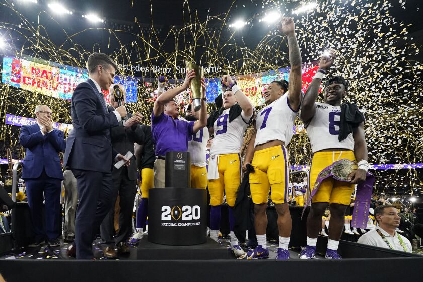 FILE - In this Jan. 13, 2020, file photo, LSU head coach Ed Orgeron holds the trophy after the team's victory over Clemson in an NCAA College Football Playoff national championship game in New Orleans. LSU has begun asking a number of football players to self-quarantine in the past week because of instances in which some players tested positive for COVID-19 after social interactions outside of the Tigers’ training facility. (AP Photo/David J. Phillip, File)