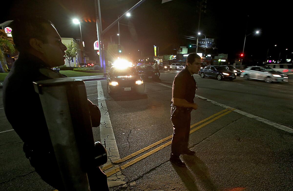 Two LAPD officers stand guard at La Brea Avenue and Venice Boulevard, about a block away from the West Traffic Division where a gunman walked into the station and opened fire.