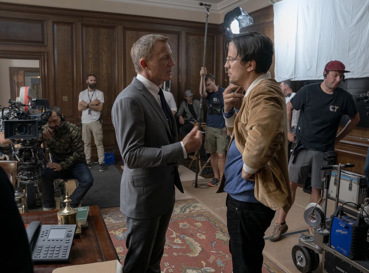This mage released by MGM shows director Cary Joji Fukunaga, right, with actor Daniel Craig on the set of the James Bond film "No Time to Die." (Nicola Dove/MGM via AP)