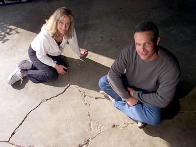 Mary Gafner with husband, Paul, next to crack in foundation of garage.