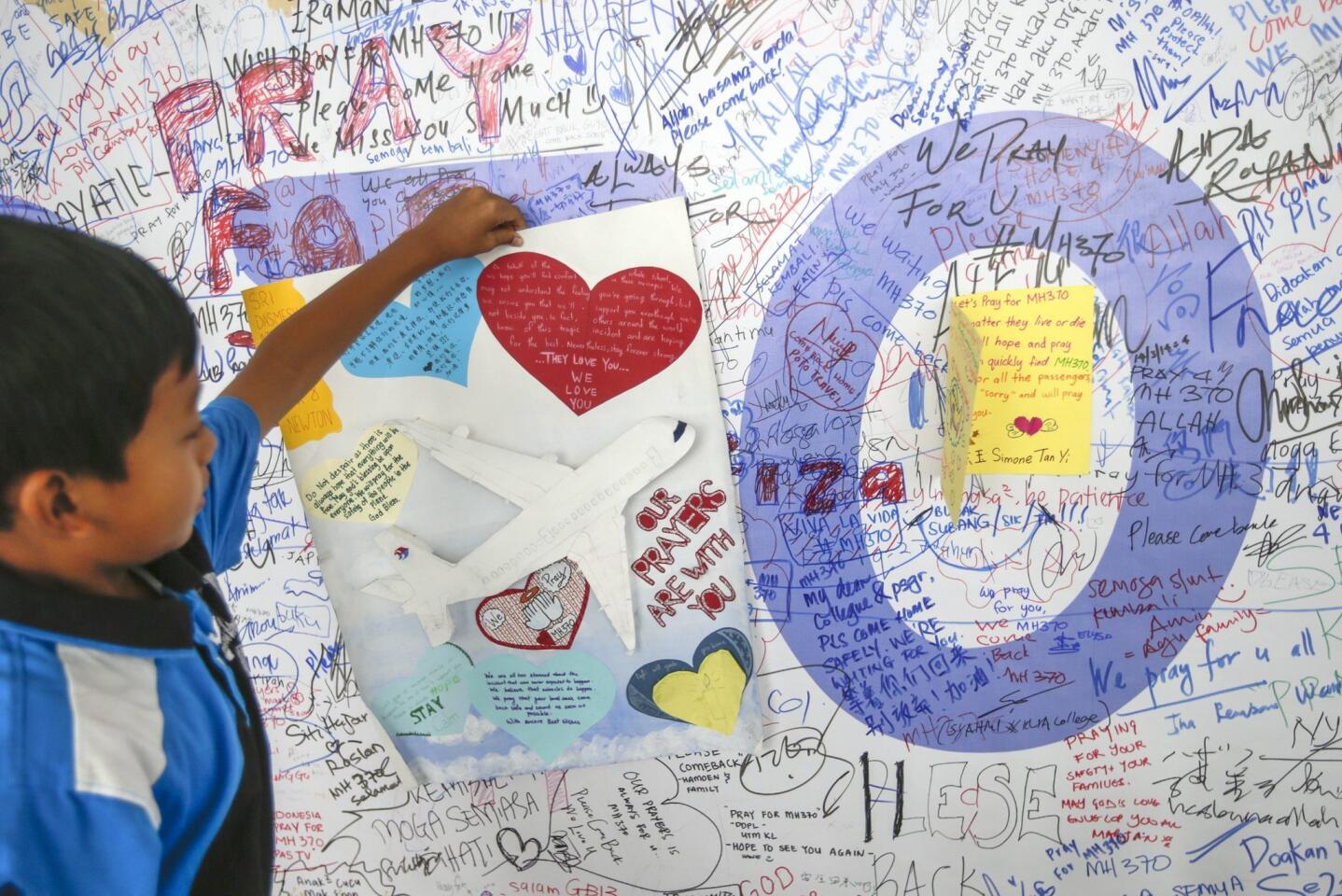 A boy holds a message at the Wall of Hope for the passengers of the missing Malaysian Airlines plane at Kuala Lumpur International Airport, Malaysia, 17 March 2014.