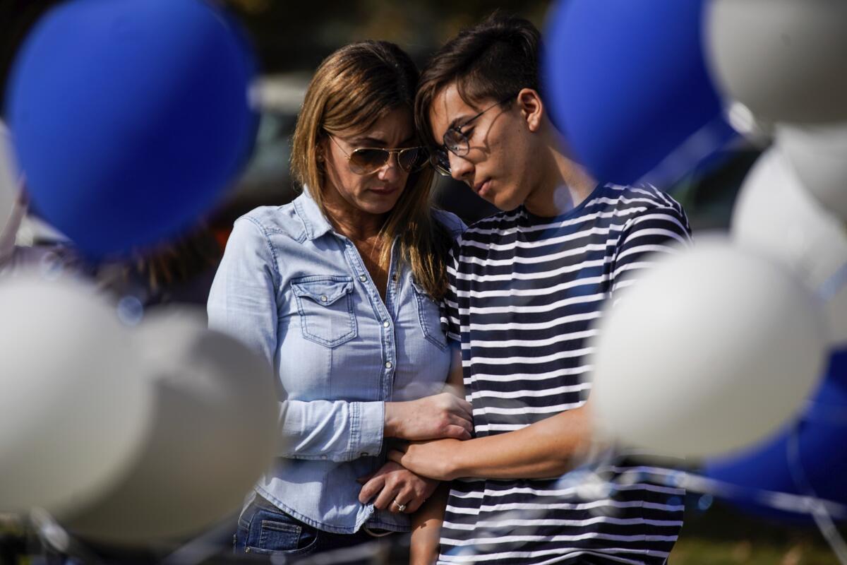 Vicky Villarreal and Matthew Arauz pay their respects at a memorial at Central Park in Santa Clarita for the victims of the shooting at Saugus High School.